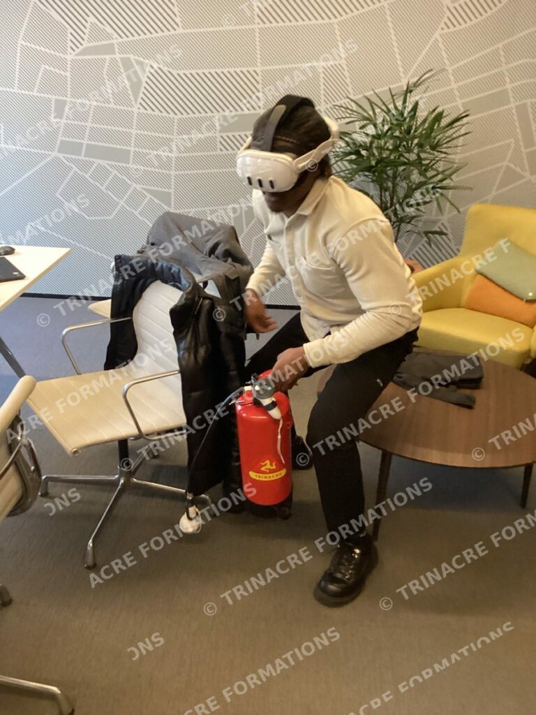 Salarié en formation incendie en réalité augmentée, en position basse, qui attaque un départ de feu virtuel avec un extincteur